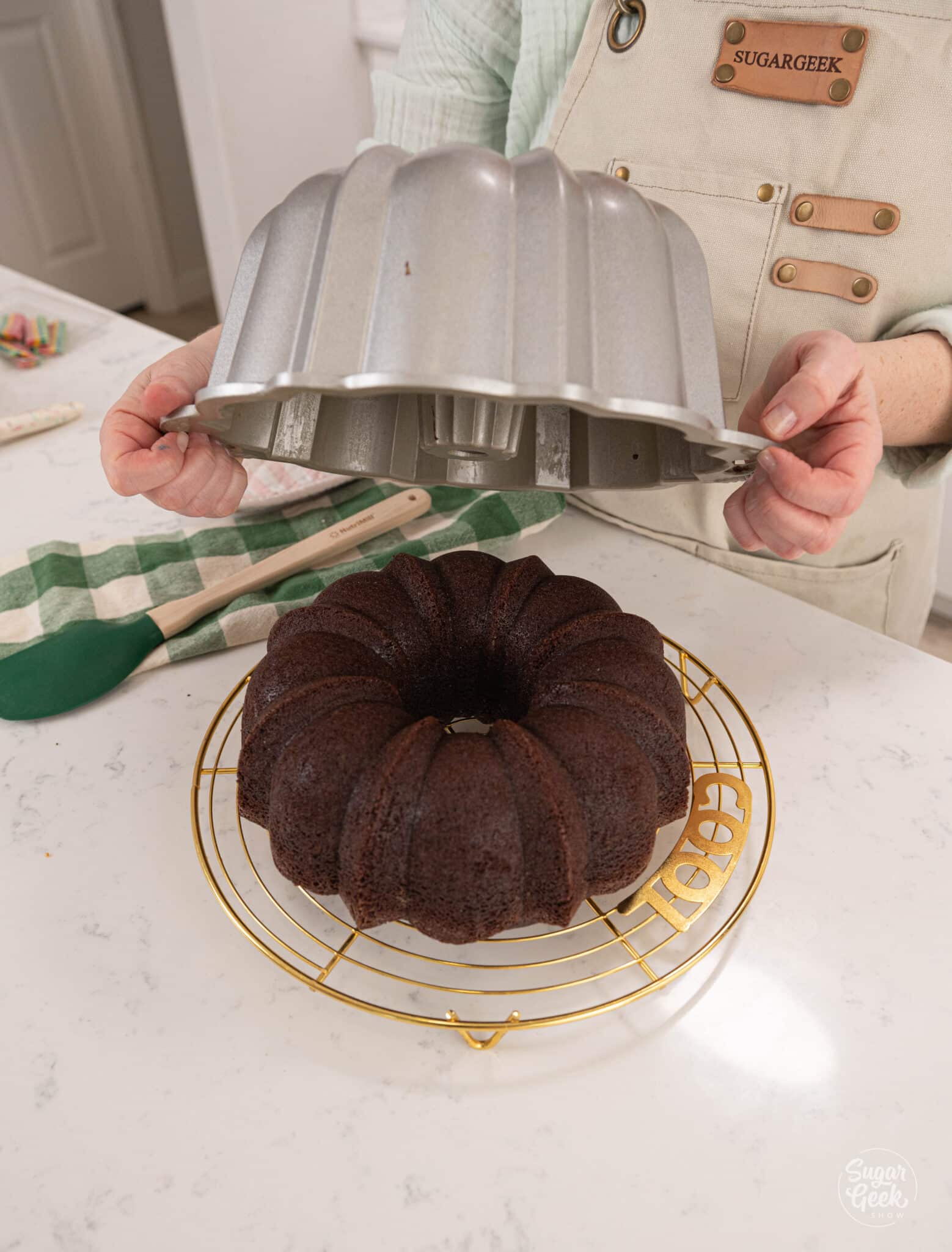 hands lifting a bundt cake pan off of a chocolate bundt cake