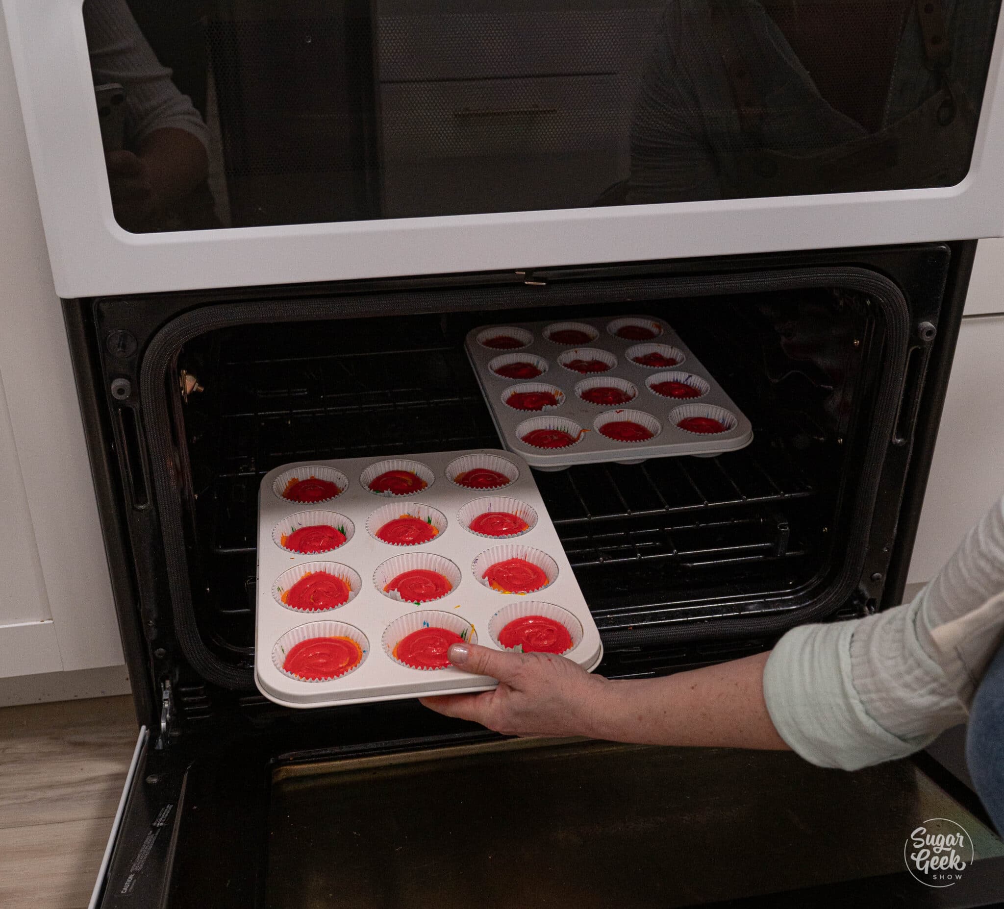 placing two cupcake trays filled with batter into the oven to bake