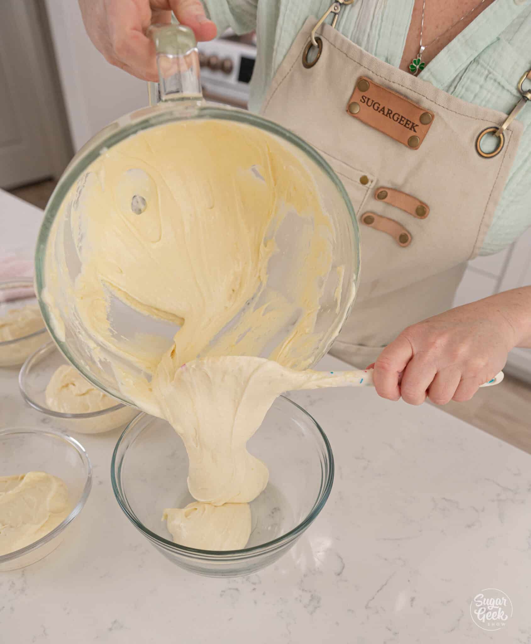 pouring cupcake batter from a large bowl into a smaller bowl