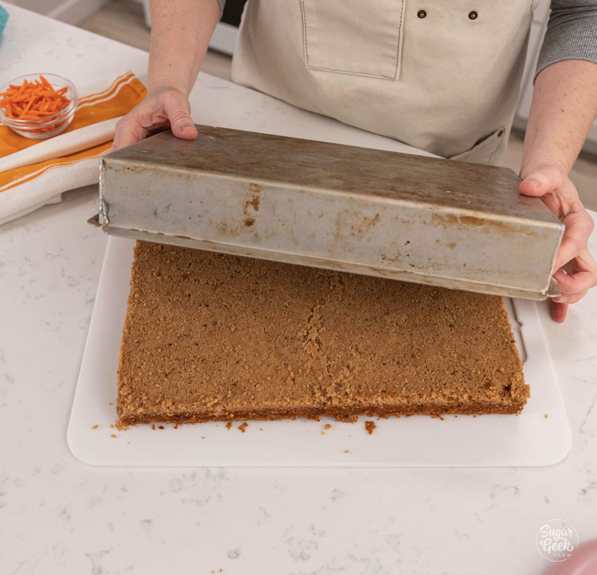 inverting a cake out of a rectangular pan onto a cutting board