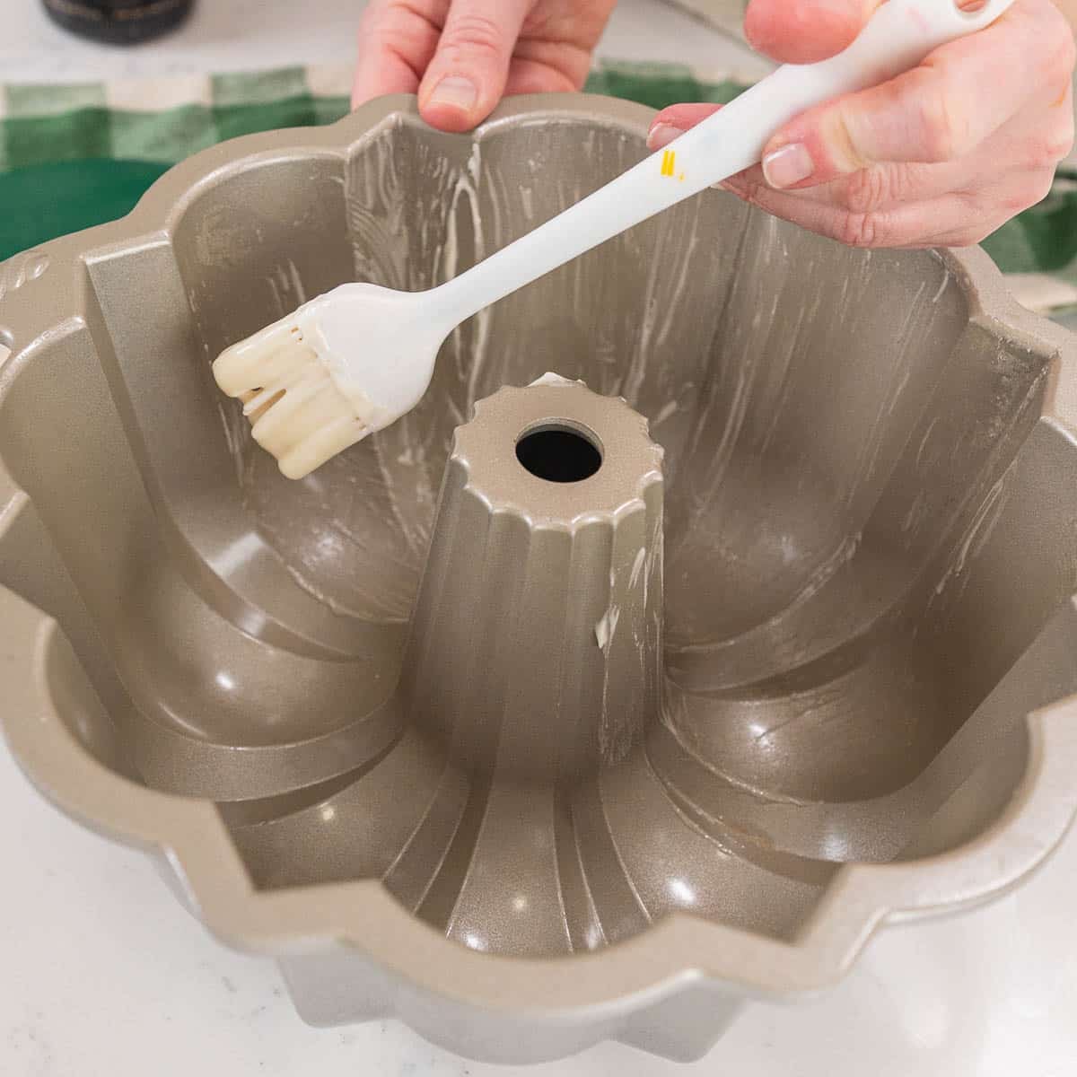 close up of bundt cake being coated with pan release