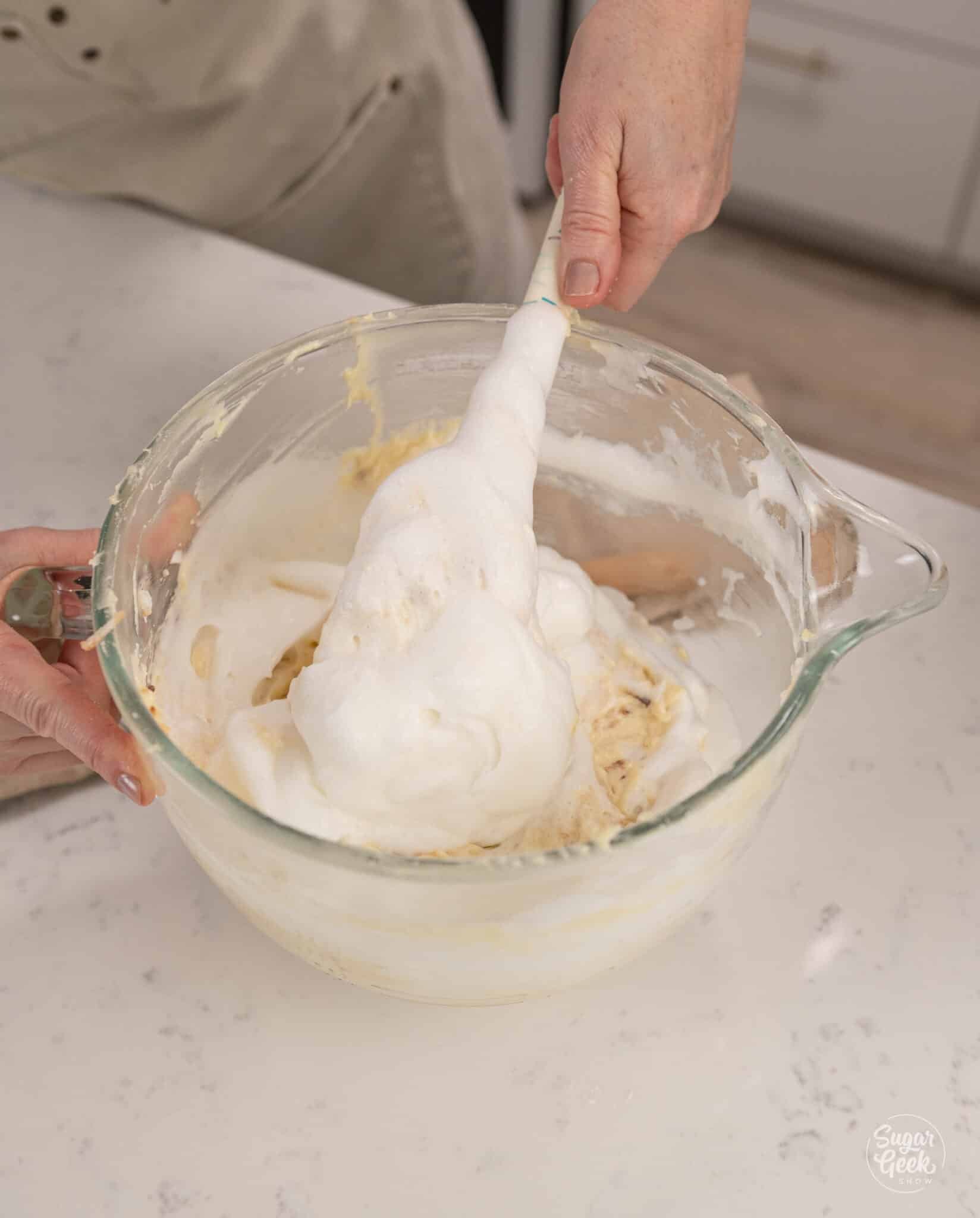hand folding meringue into cake batter with a spatula