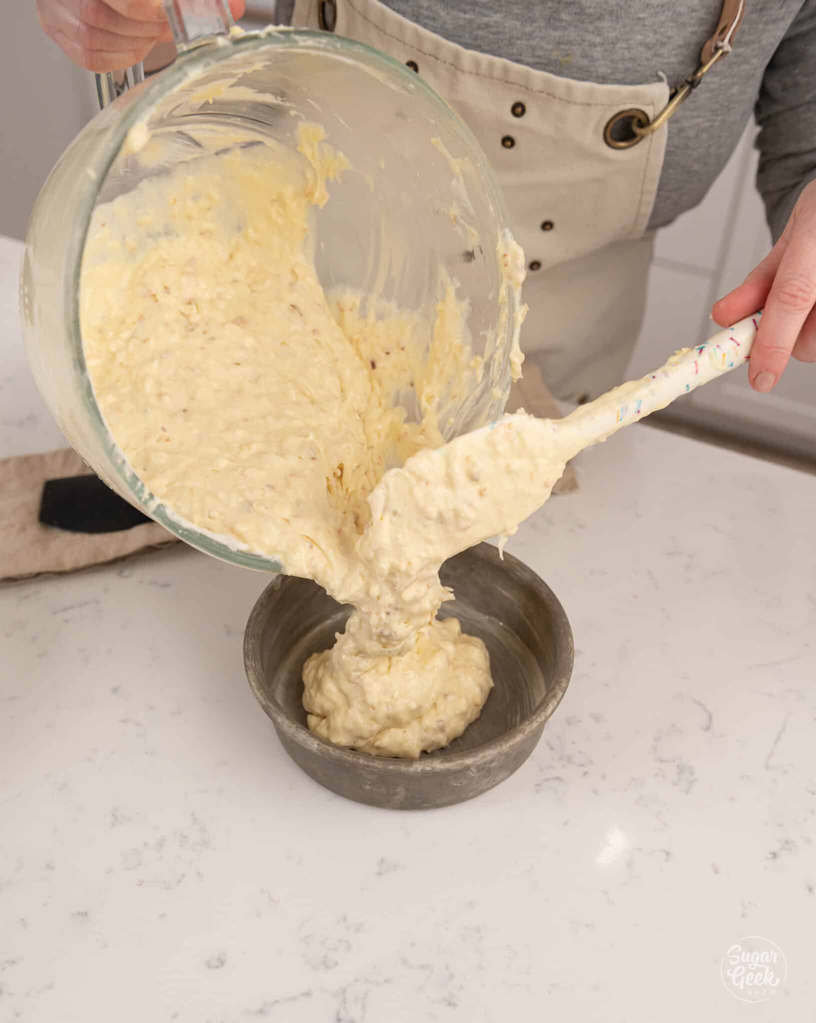 pouring coconut cake batter into a cake pan