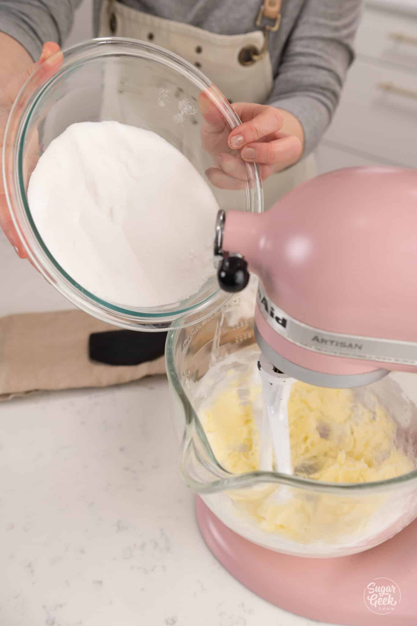 adding a bowl of sugar to a glass stand mixer bowl