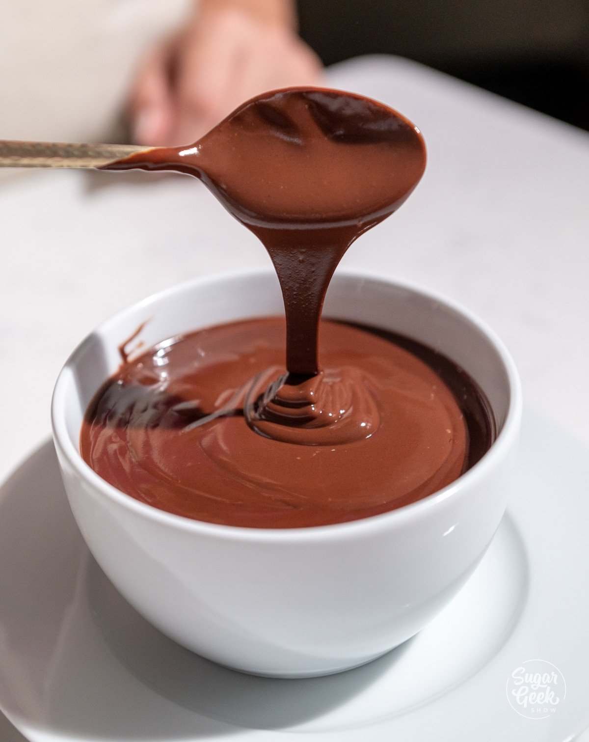 soft chocolate ganache drizzling from a spoon into a bowl