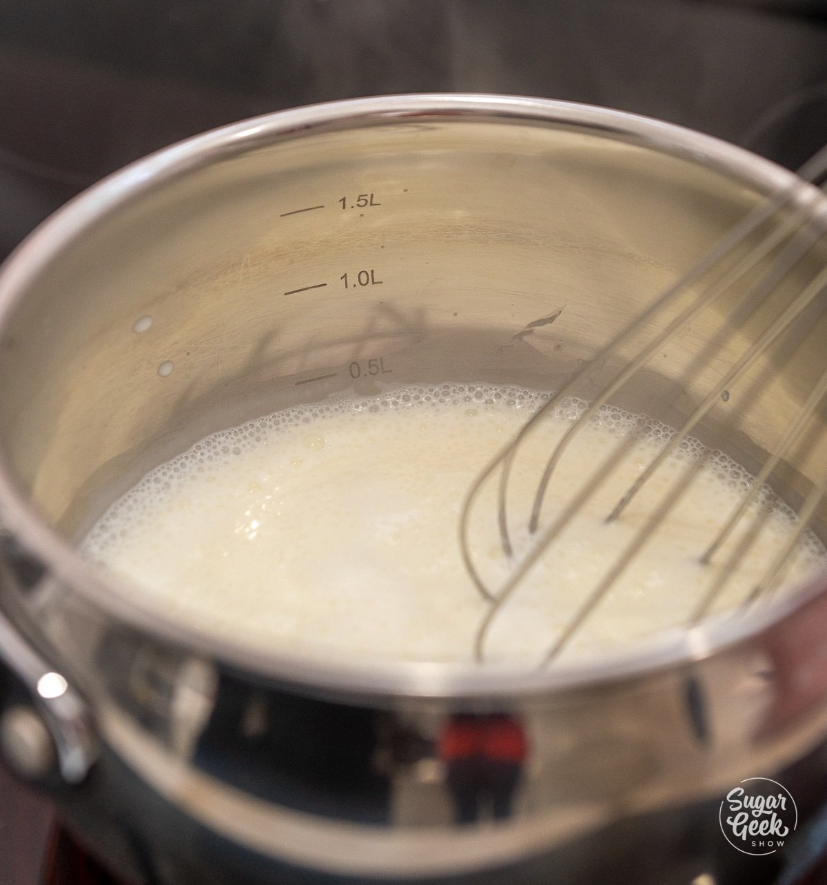 saucepan of heavy cream on the stove with a whisk stirring