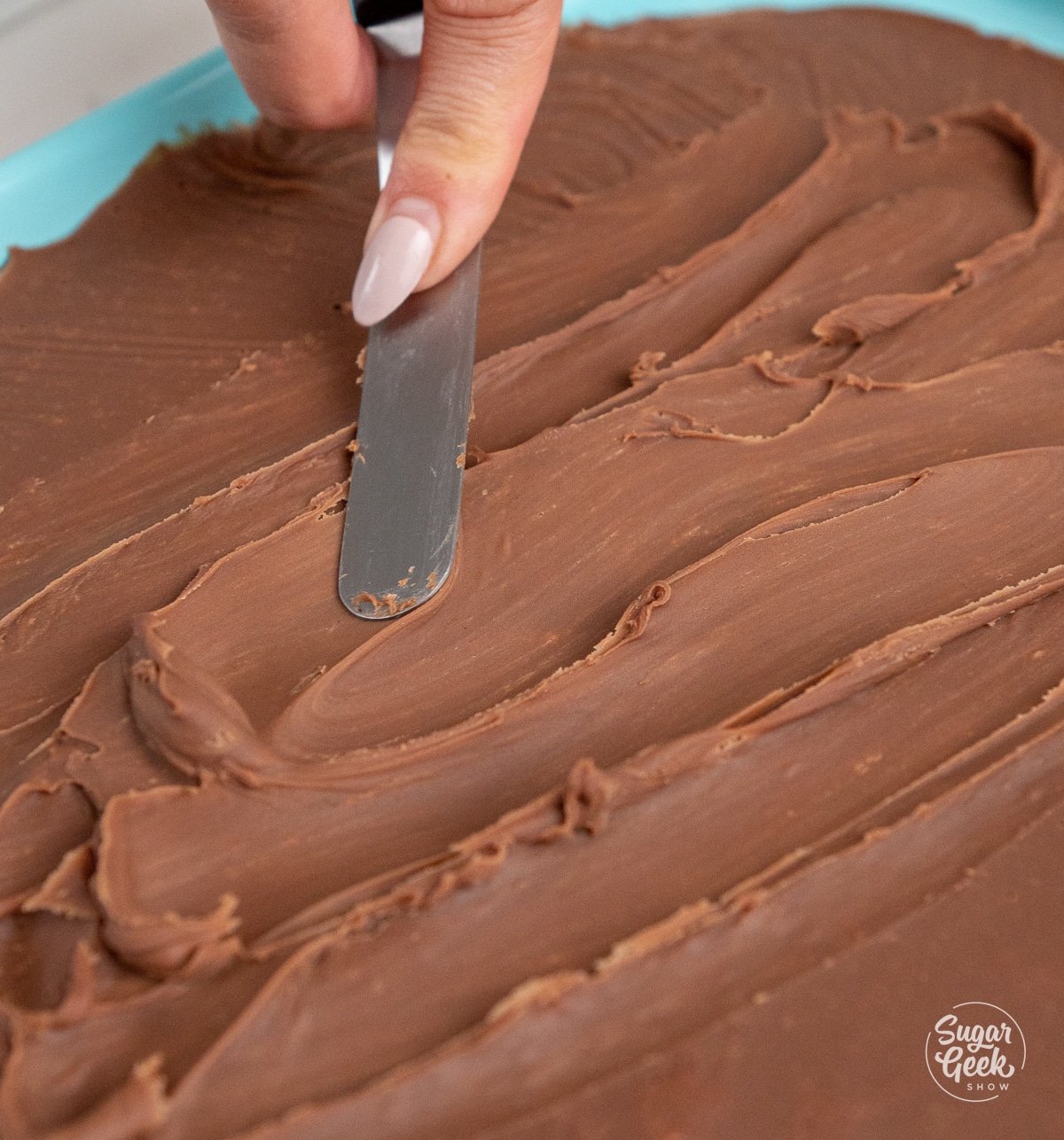 hand spreading out ganache with a spatula