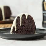 chocolate bundt cake with a white drip on a black plate