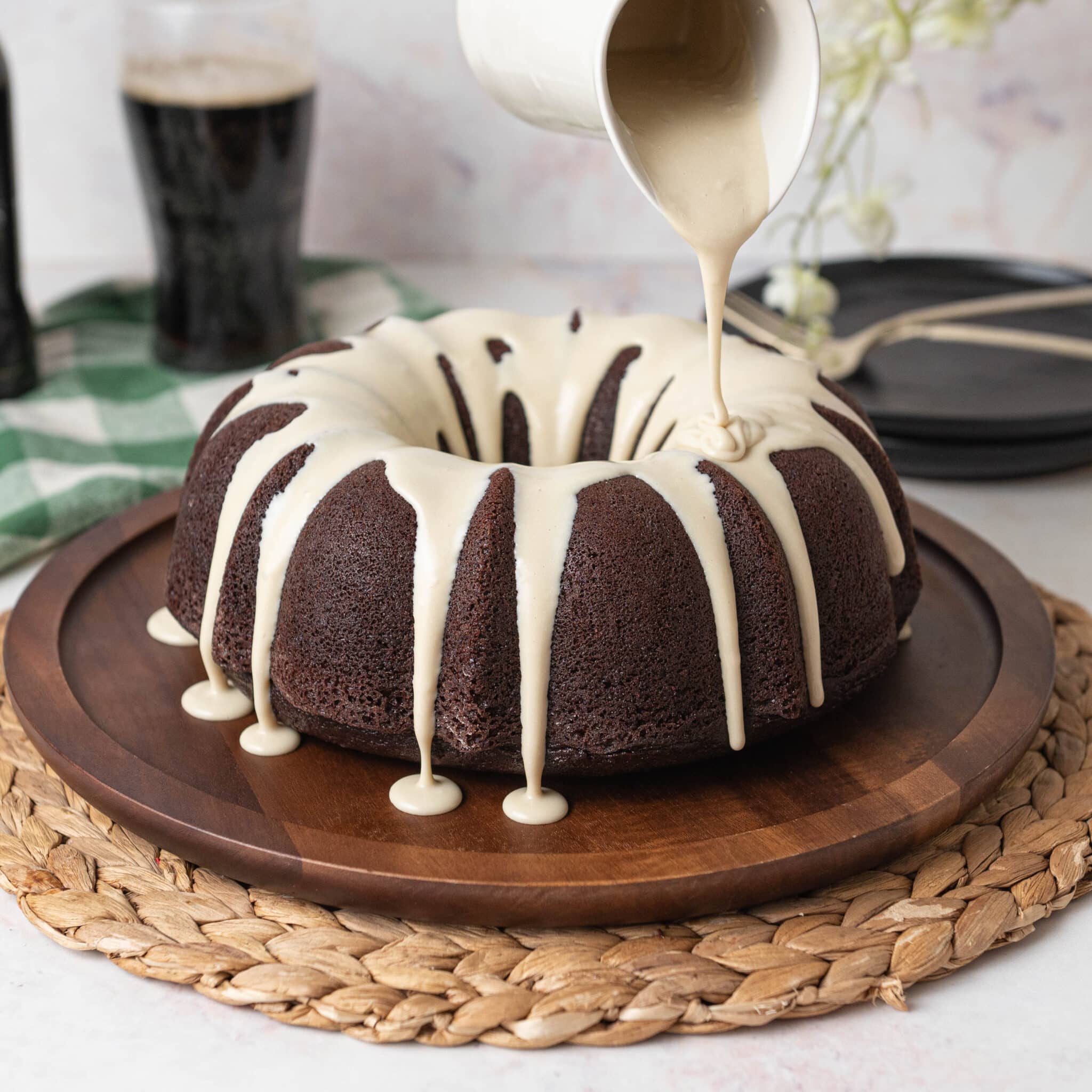 drizzling white chocolate ganache on top of a chocolate bundt cake