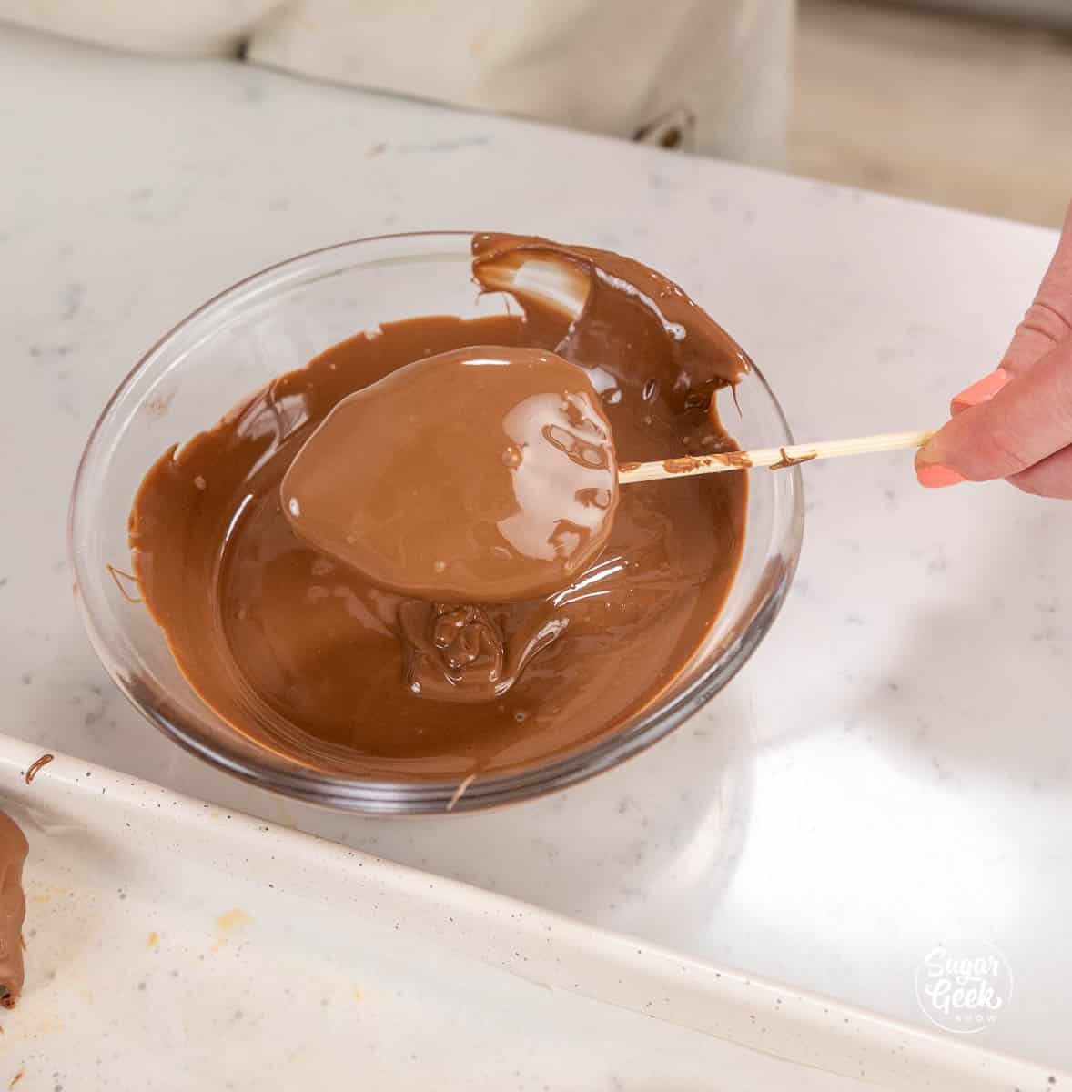 Dipping a peanut butter egg in chocolate with a skewer