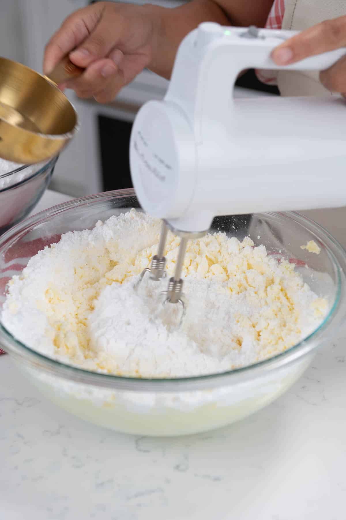 mixing butter and powdered sugar in a large bowl