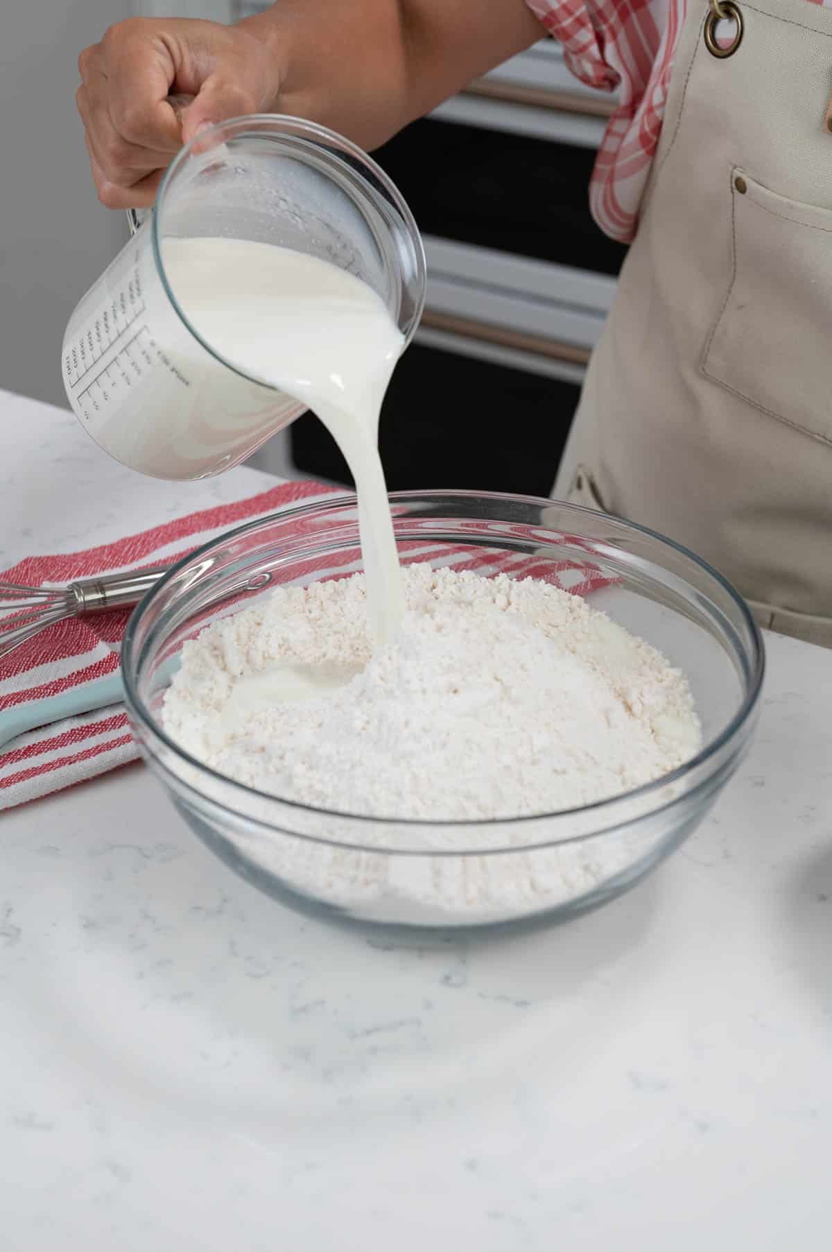 pouring milk into a bowl of pancake mix