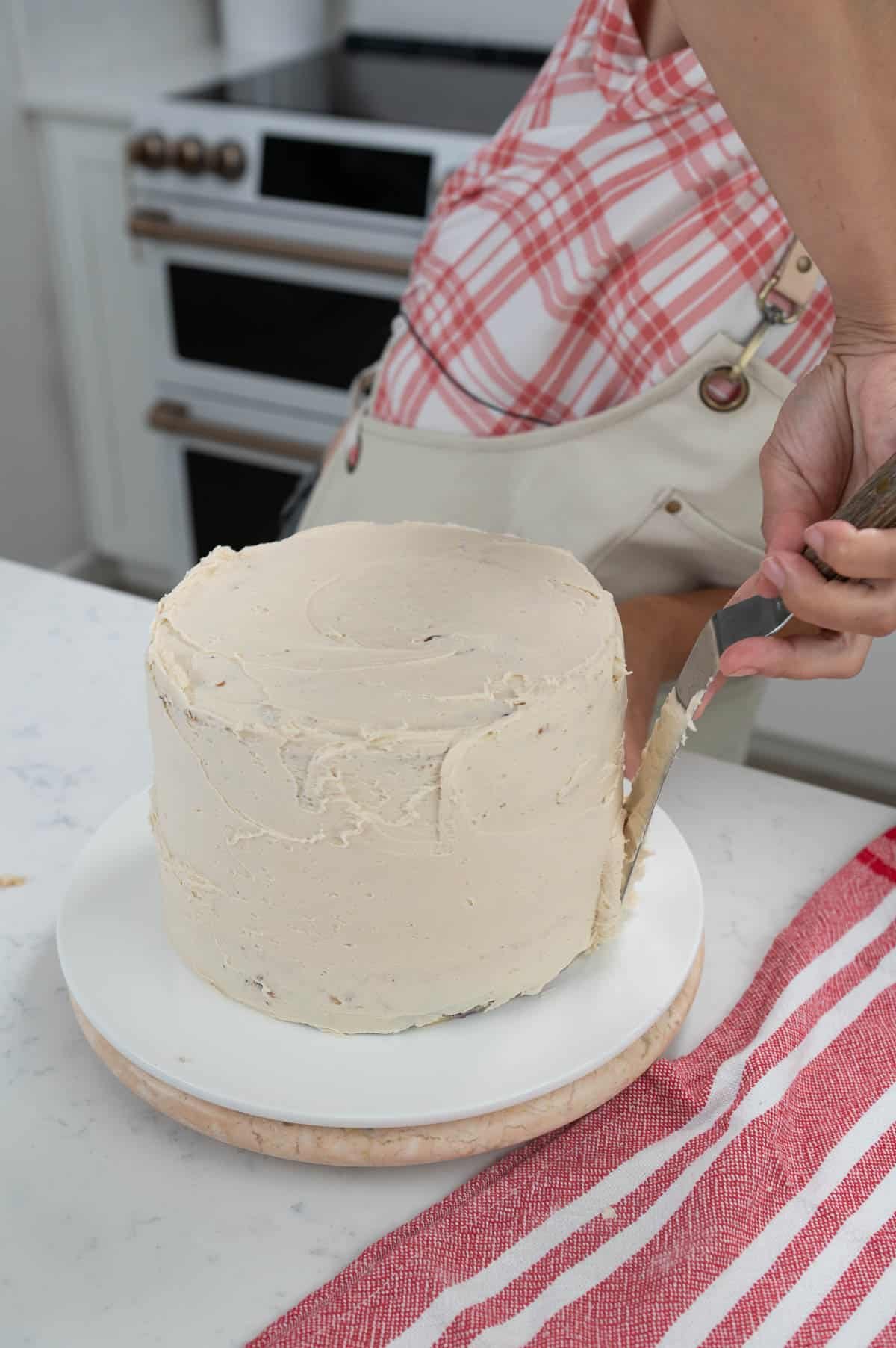 spreading a crumb coat of frosting on a cake