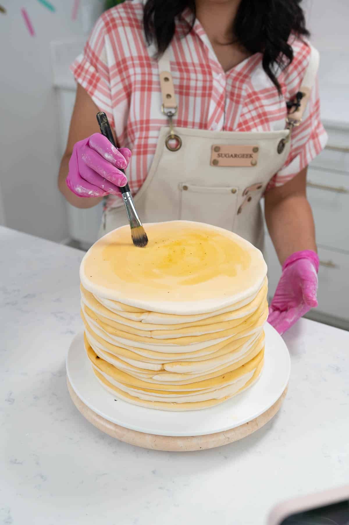 brushing food color onto fondant on top of a cake