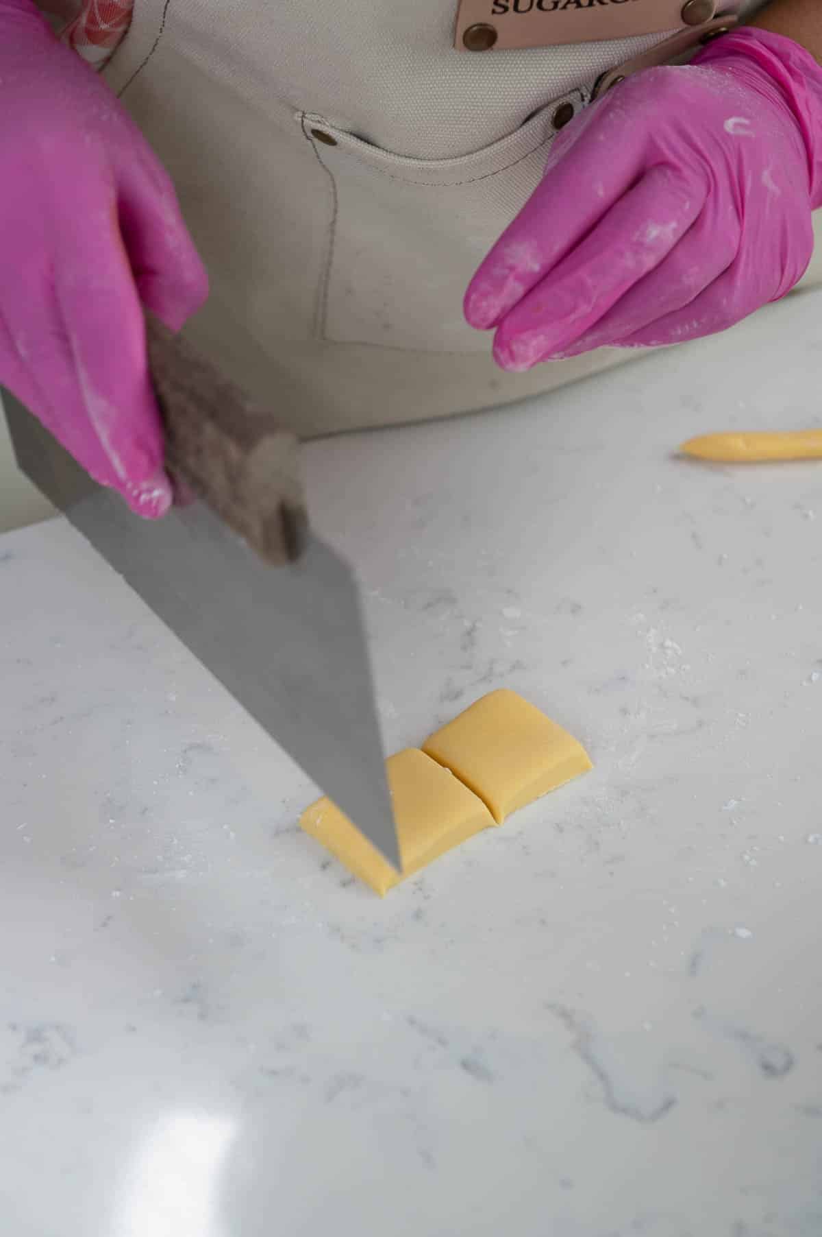 cutting yellow fondant squares with a bench scraper