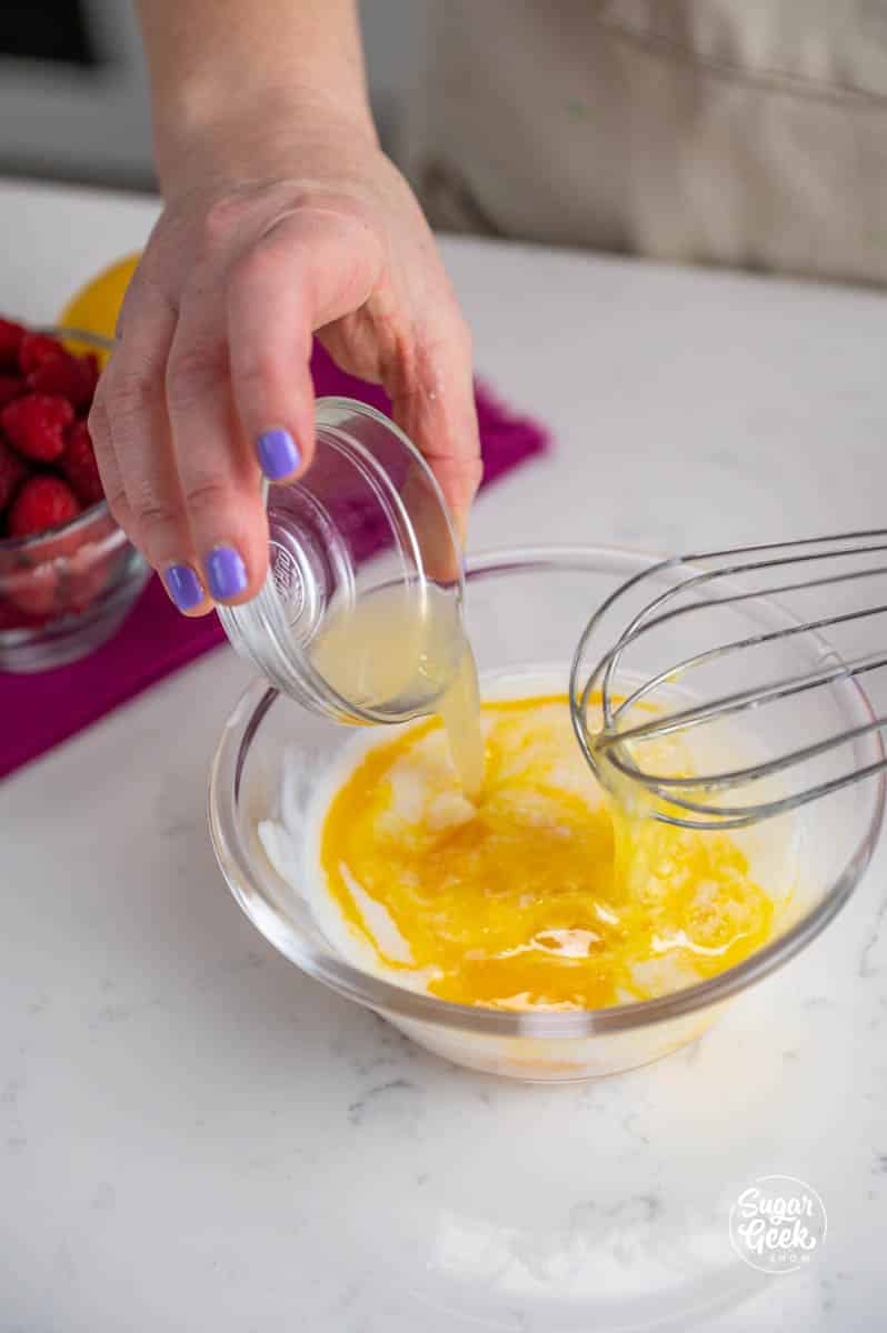 hand pouring lemon into a bowl of eggs