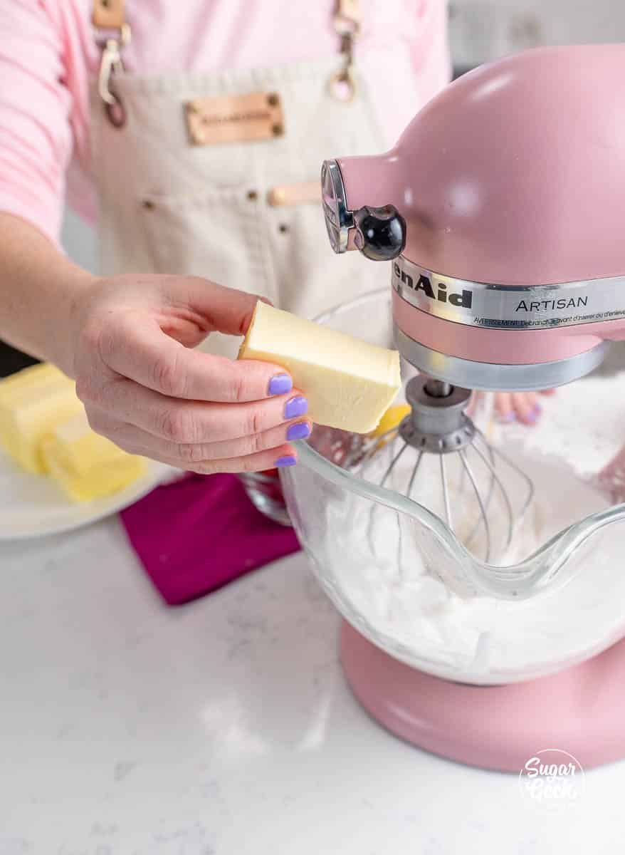 hand adding a stick of butter to a stand mixer bowl