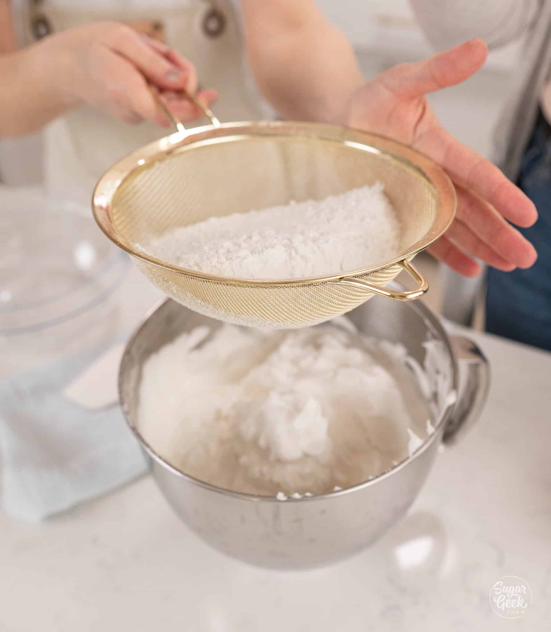 sifting dry ingredients into a bowl of meringue