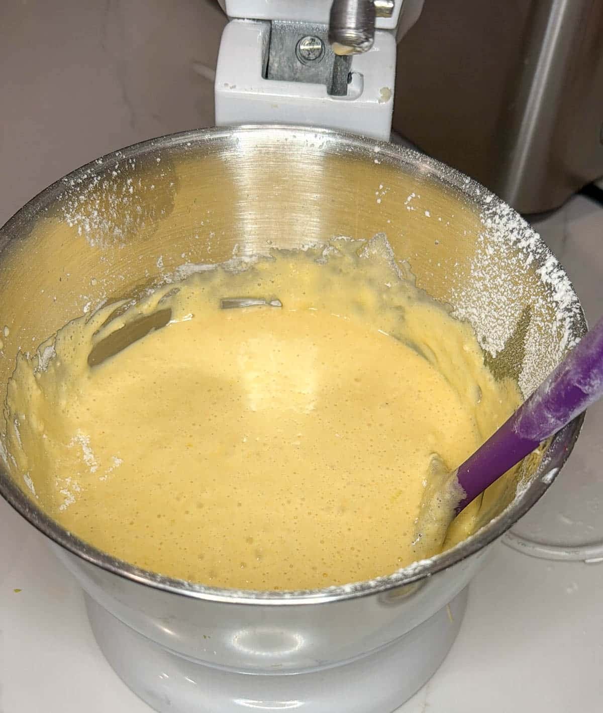 Close up of lemon olive oil cake batter in the bowl of a stand mixer.
