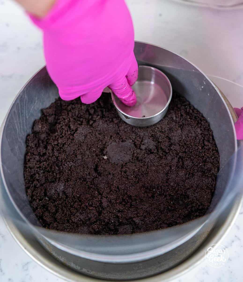 spreading cookie crumbs into the base of a cake pan