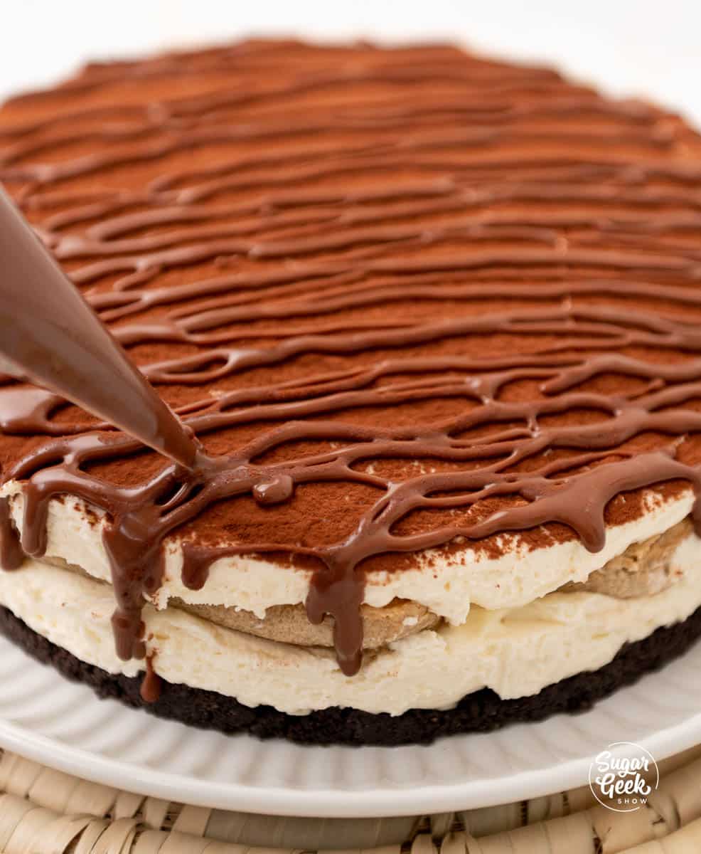 piping ganache on top of a cheesecake