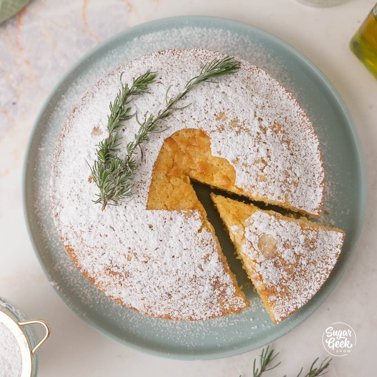 Powdered sugar dusted olive oil cake with a slice taken out of it.