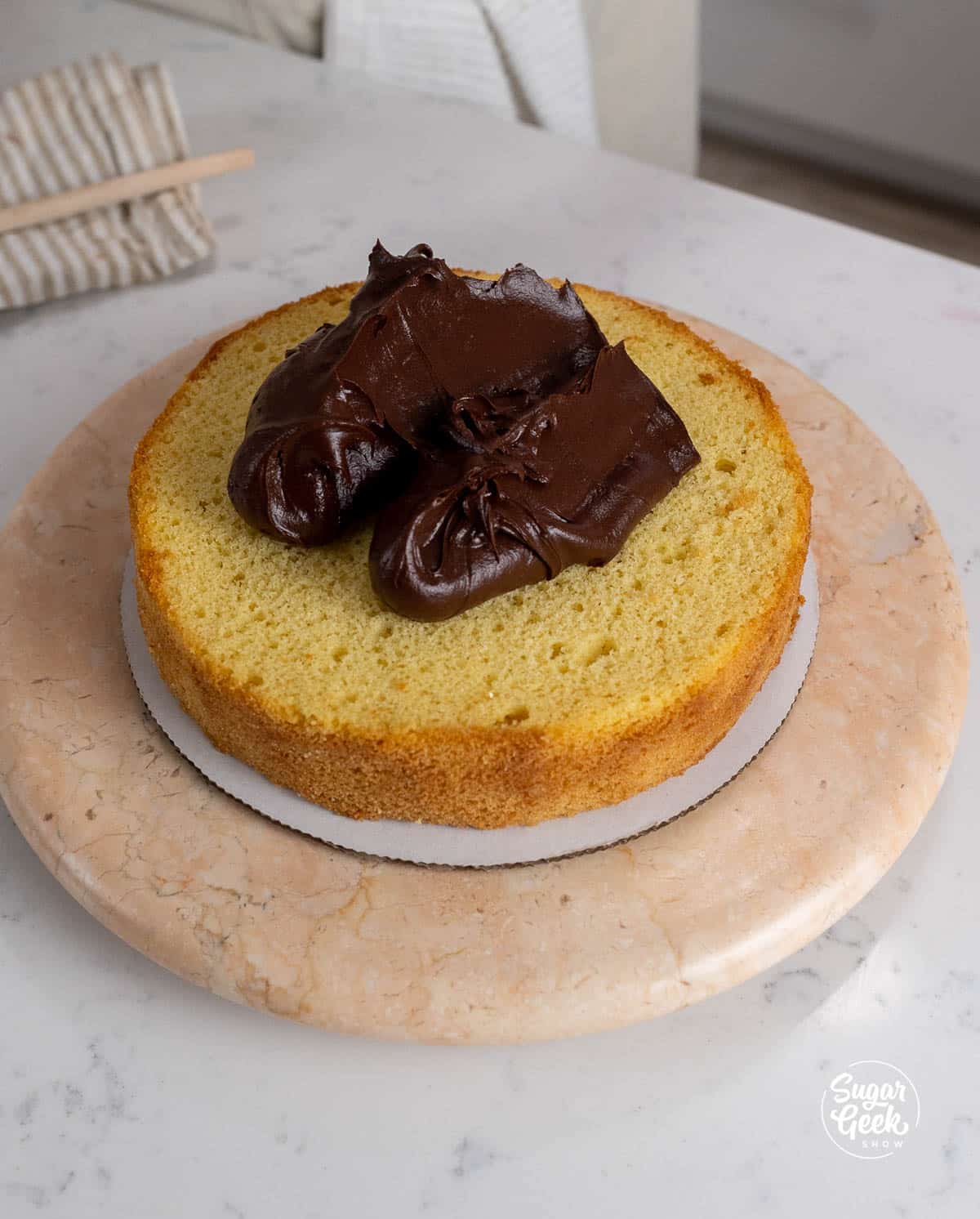 one layer of yellow cake with chocolate frosting on a cardboard round