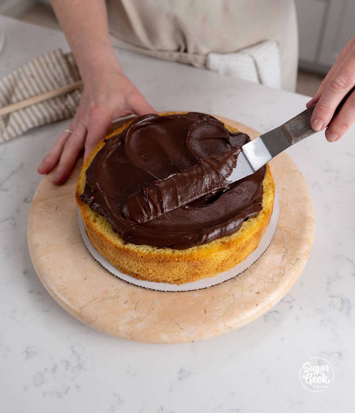 spatula spreading chocolate frosting on a cake