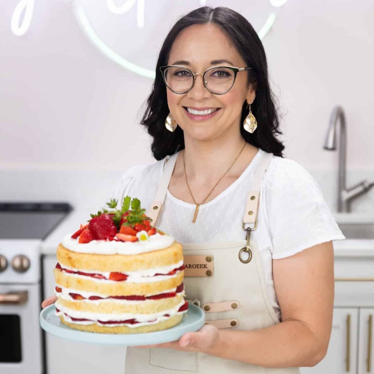 smiling woman holding a decorated cake in her hands