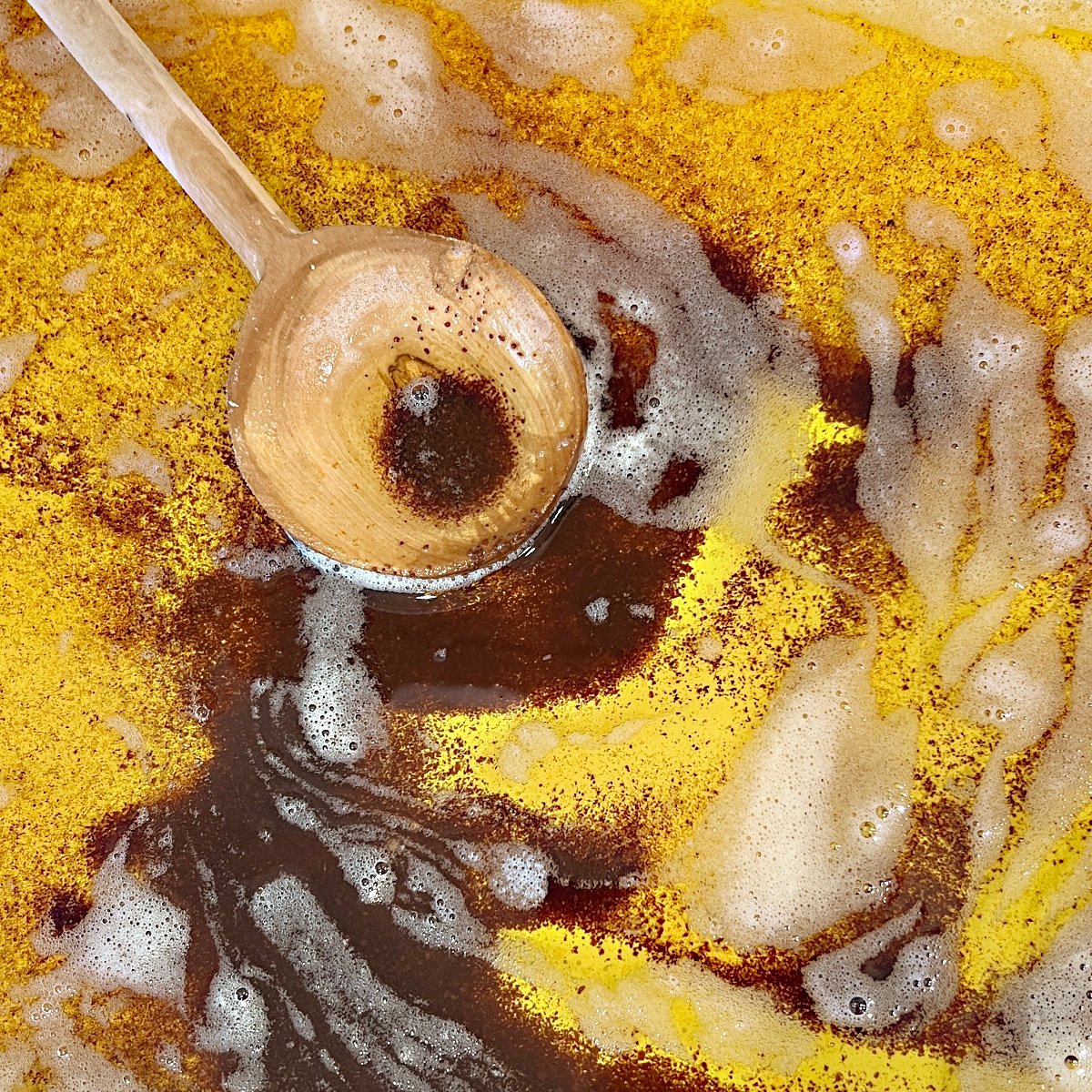 close up of browned butter in a skillet with a wooden spoon