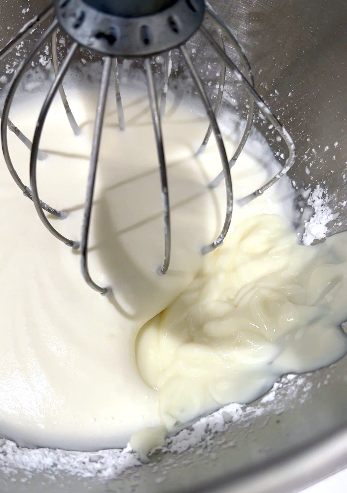 whipped cream and yogurt in a mixing bowl with whisk