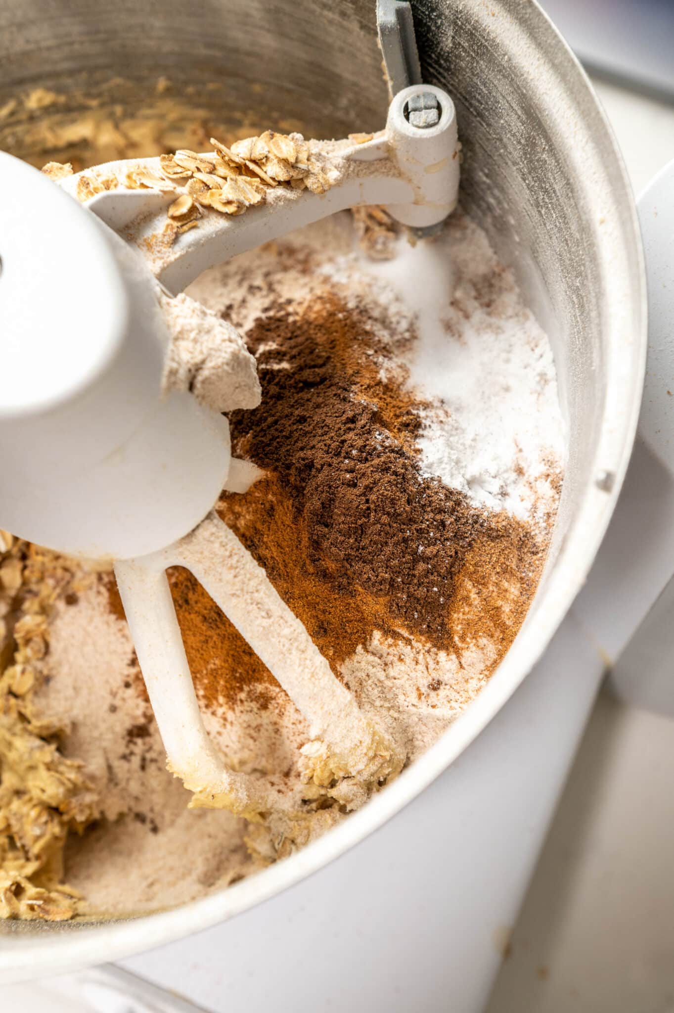 Close up oatmeal raisin m&m cookie dry ingredients in the bowl of a stand mixer