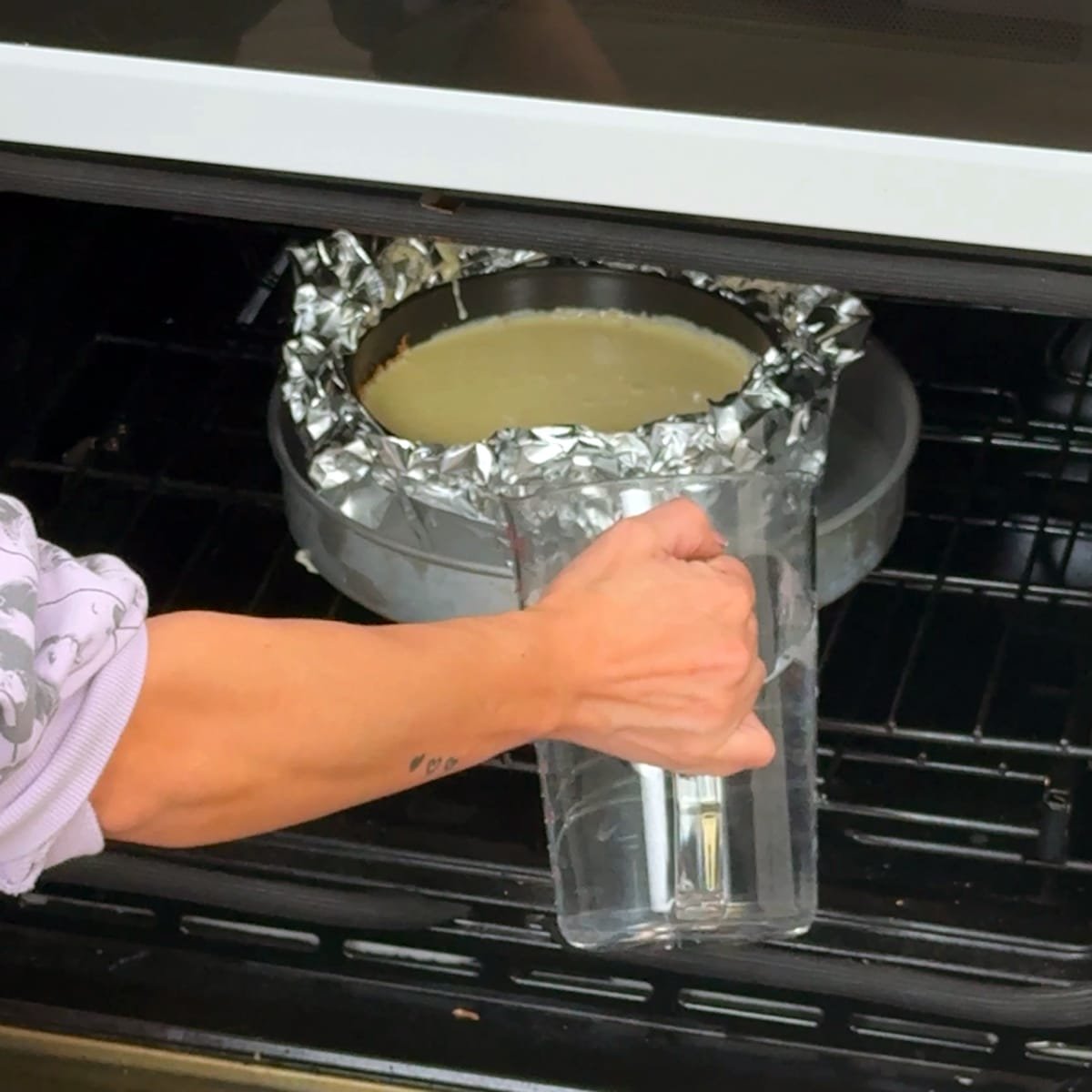 closeup of making a cheesecake water bath in an oven