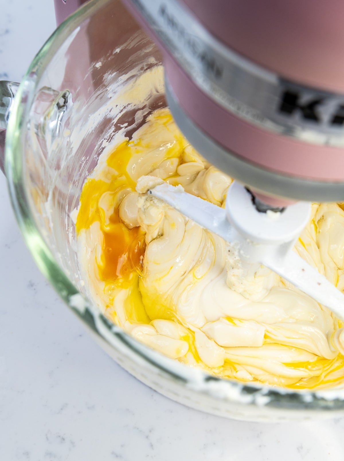 close up of cheesecake filling with eggs in the bowl of a stand mixer