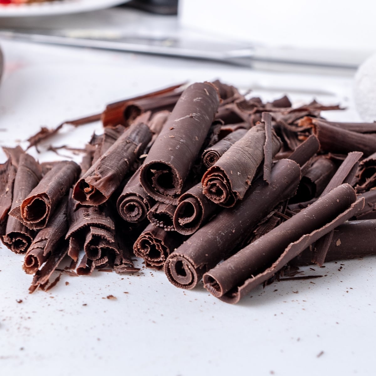 Close up of chocolate curls on a white countertop.
