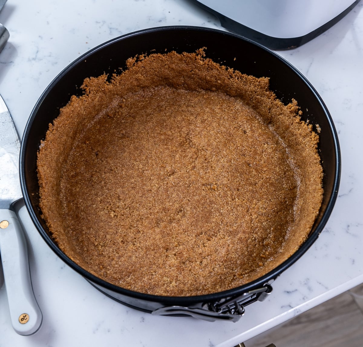Graham cracker mixture pressed into the bottom of a cheesecake pan.