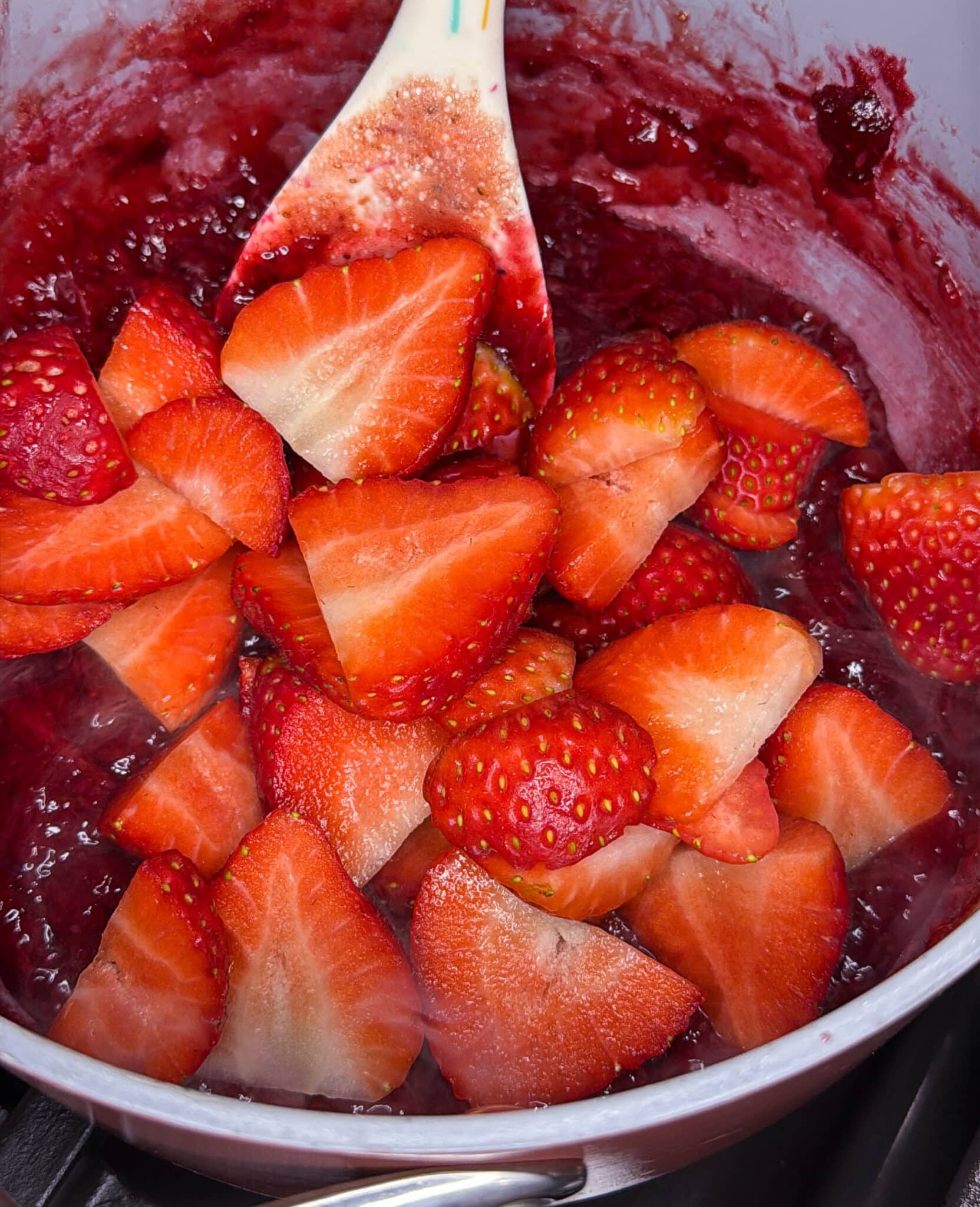 freshly sliced strawberries in a saucepan with strawberry reduction