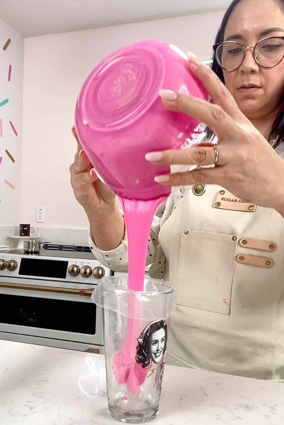 Pouring pink ganache into a piping bag.