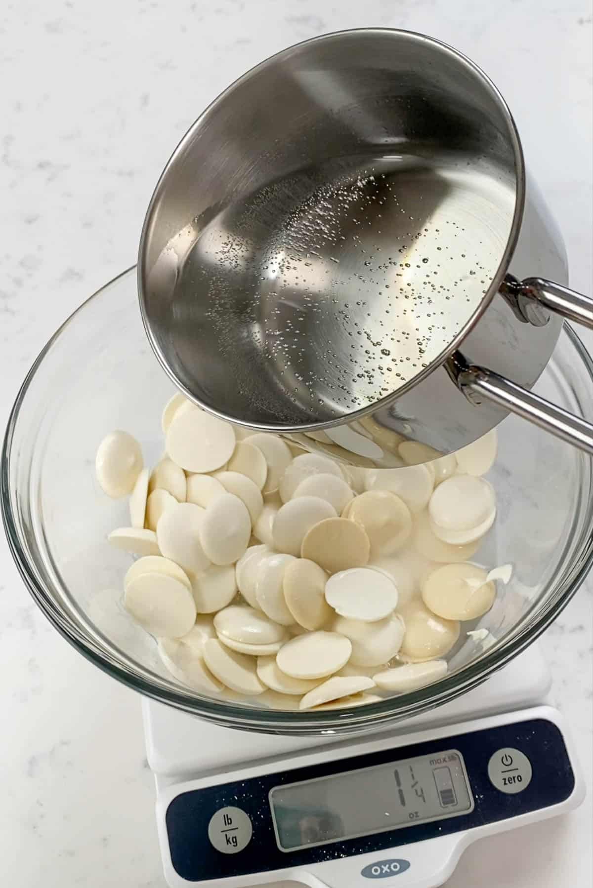 Saucepan pouring hot water onto a bowl of white candymelts.