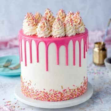 Festive cake with sprinkles and a pink drip with sprinkles on top.
