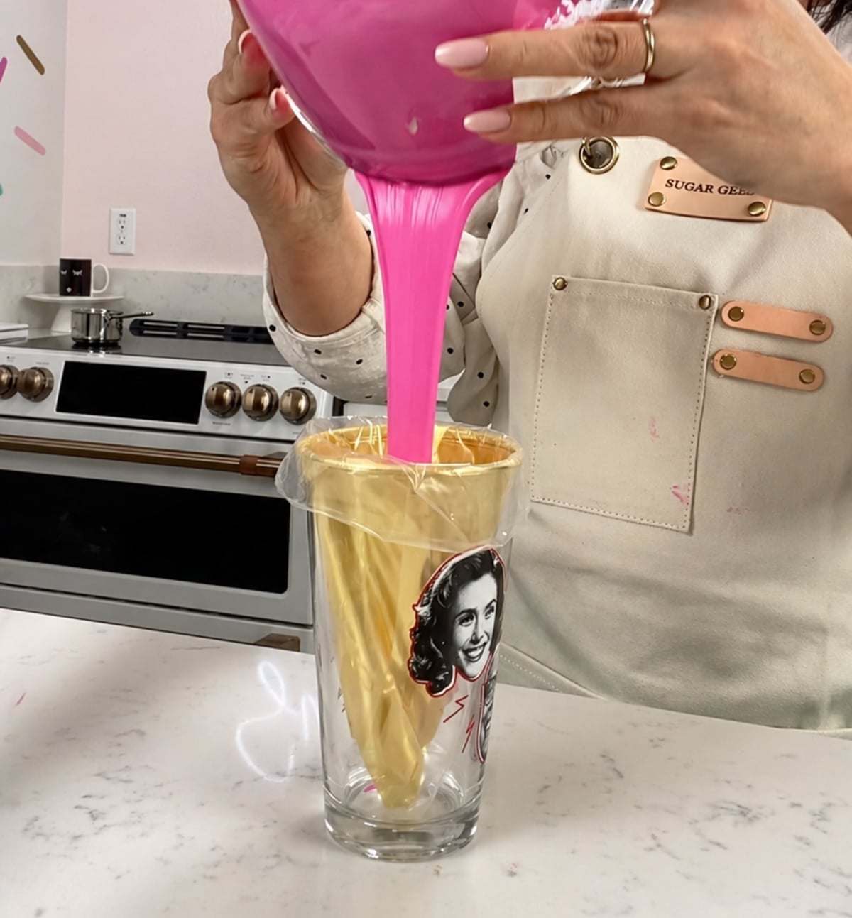 Pouring pink ganache into a piping bag lined with gold.