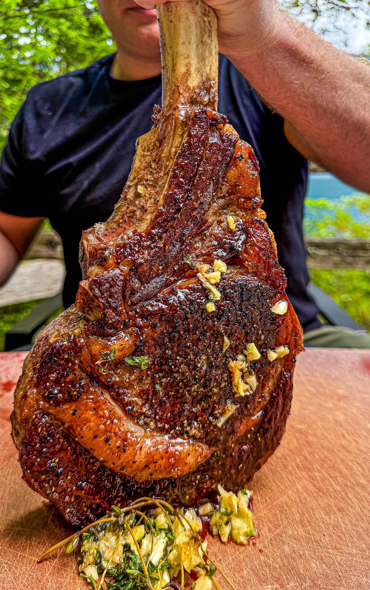 close up of a man holding a grilled tomahawk steak