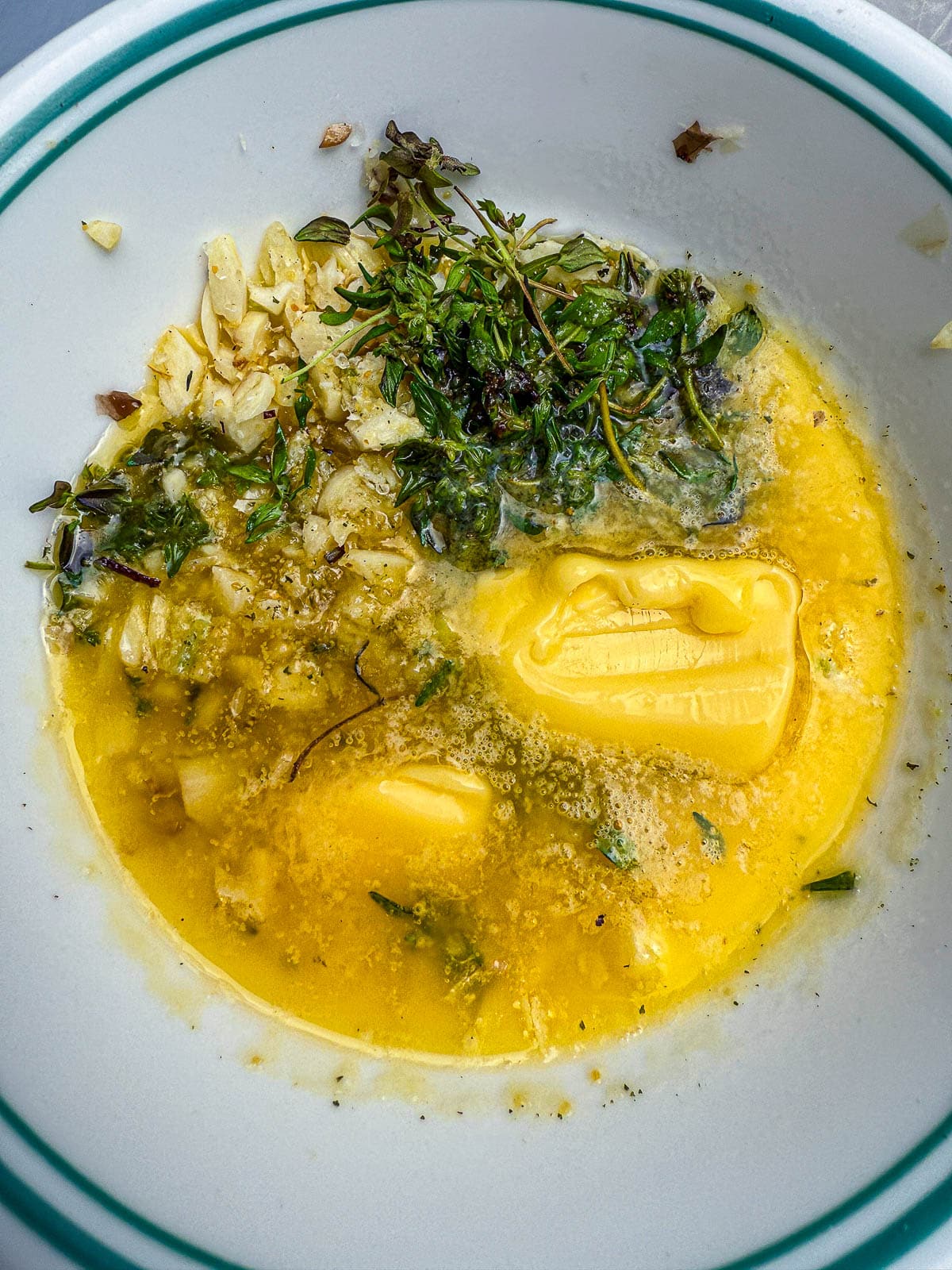 close up of melted butter, thyme, garlic, and salt