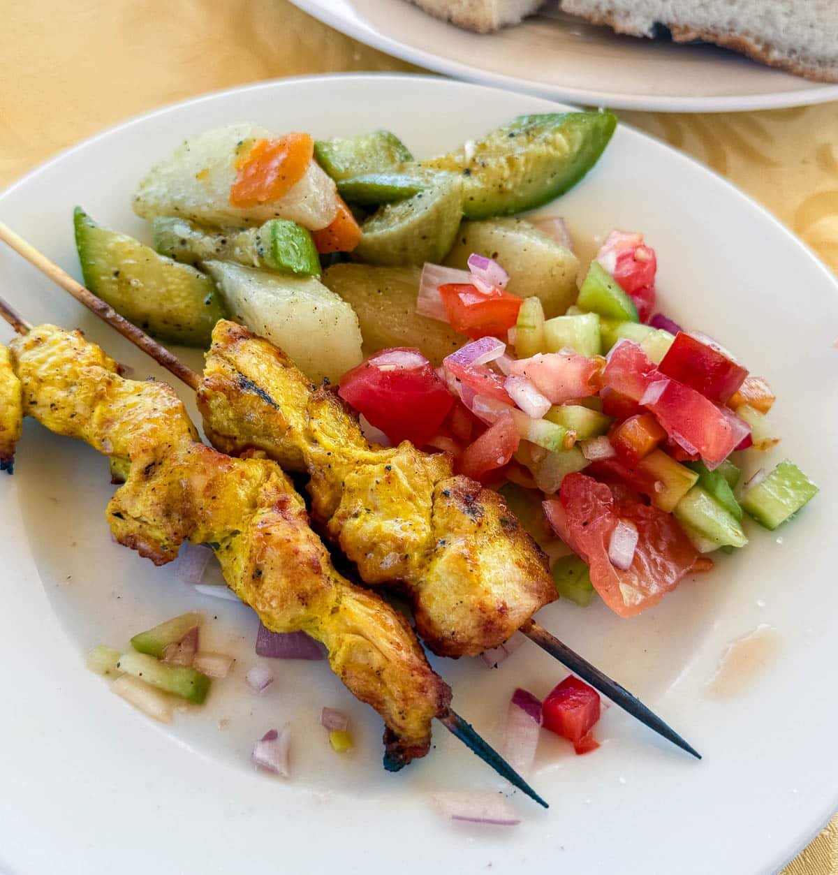 close up of moroccan tomato salad on a plate with chicken kebabs