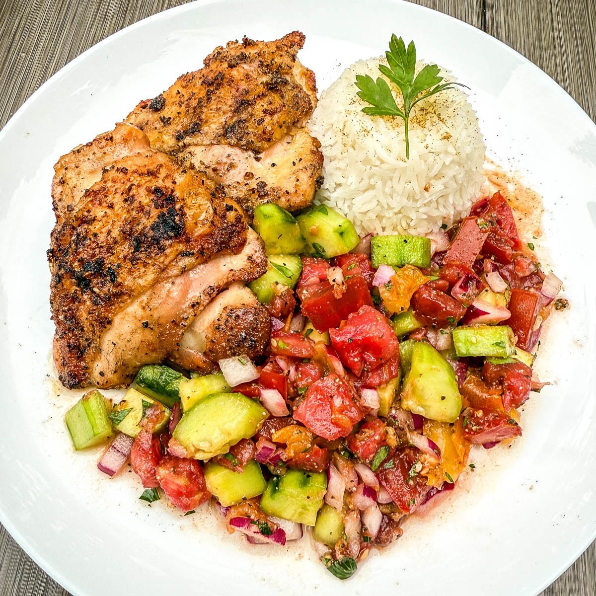 moroccan tomato salad, rice, and chicken on a white plate