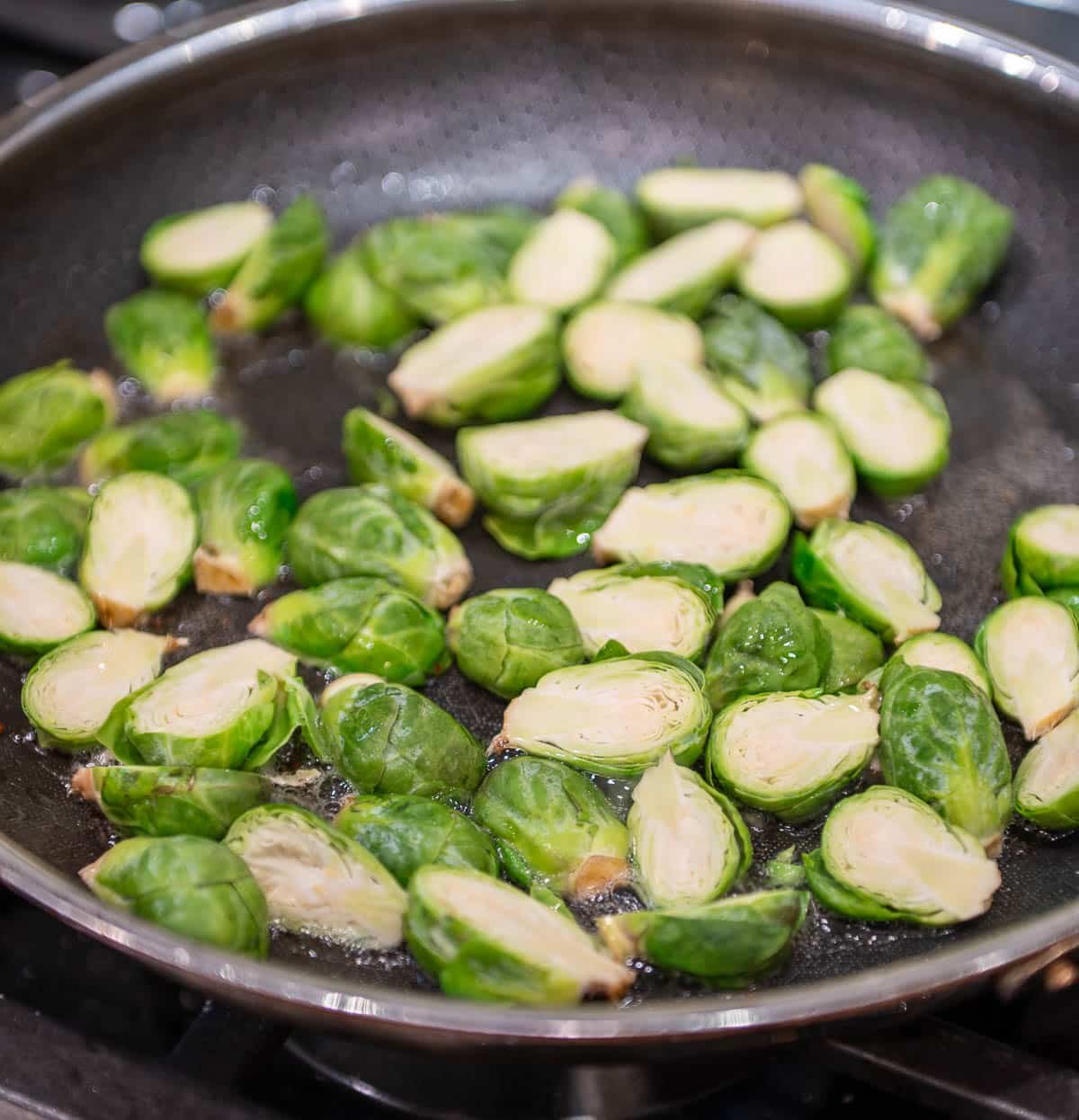 Halved Brussel sprouts cooking in the leftover bacon grease.