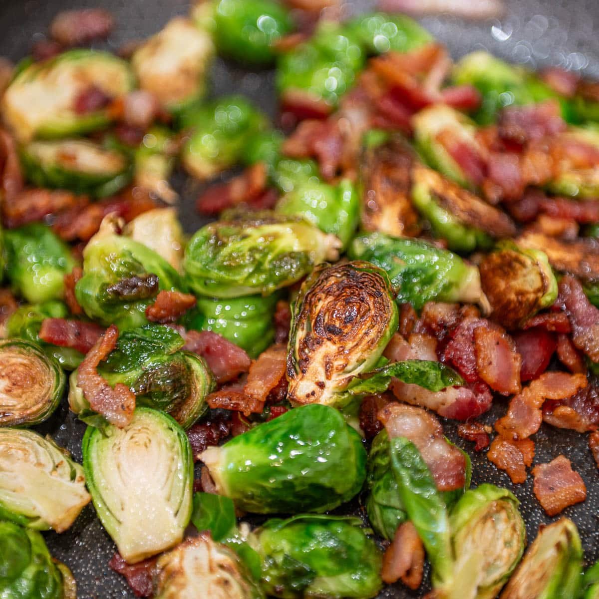 Cooked Brussel sprouts with bacon in a skillet.