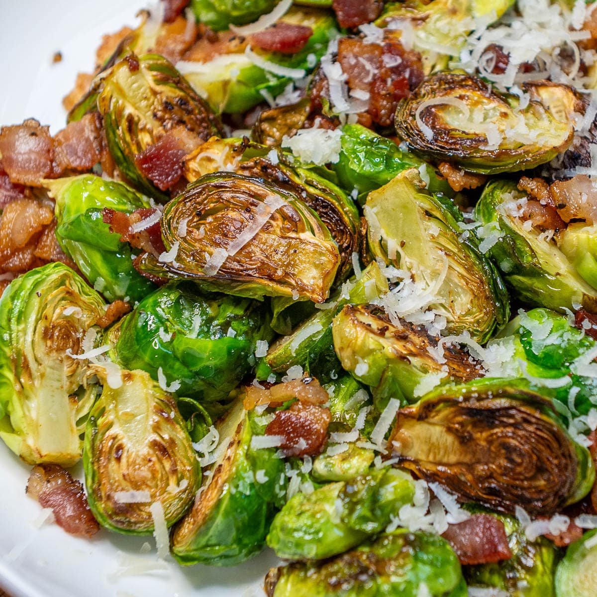 Cooked Bacon Brussel Sprouts on a plate with freshly grated Parmemsan cheese sprinkled on top. 