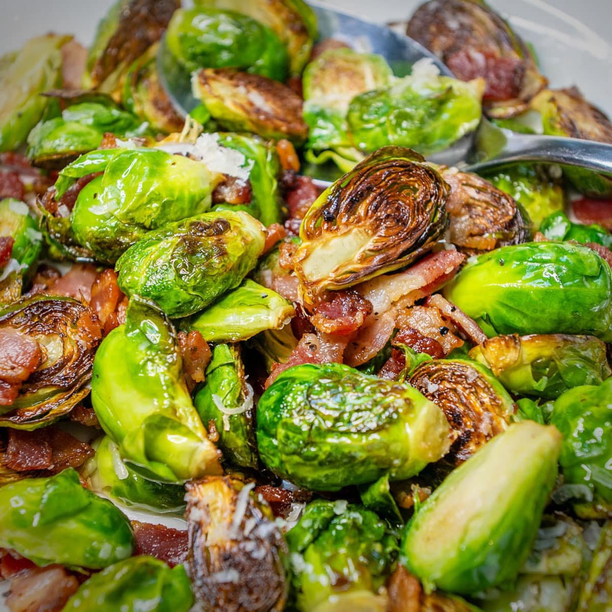 Bacon Brussel Sprouts on a plate with freshly grated Parmesan cheese sprinkled over the top.