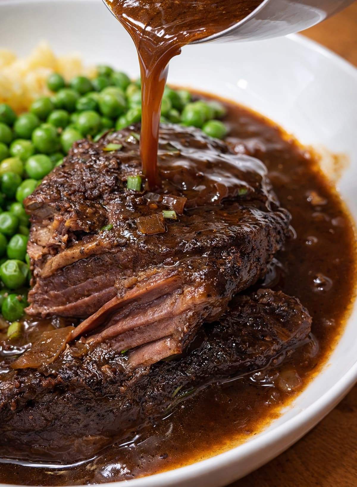 red wine reduction being poured over beef short ribs on a plate